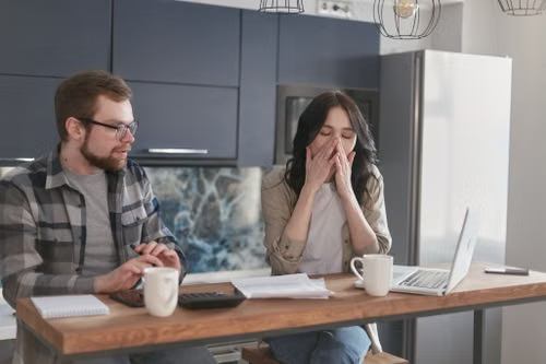 A stressed couple reviewing documents after falling victim to an online scam.